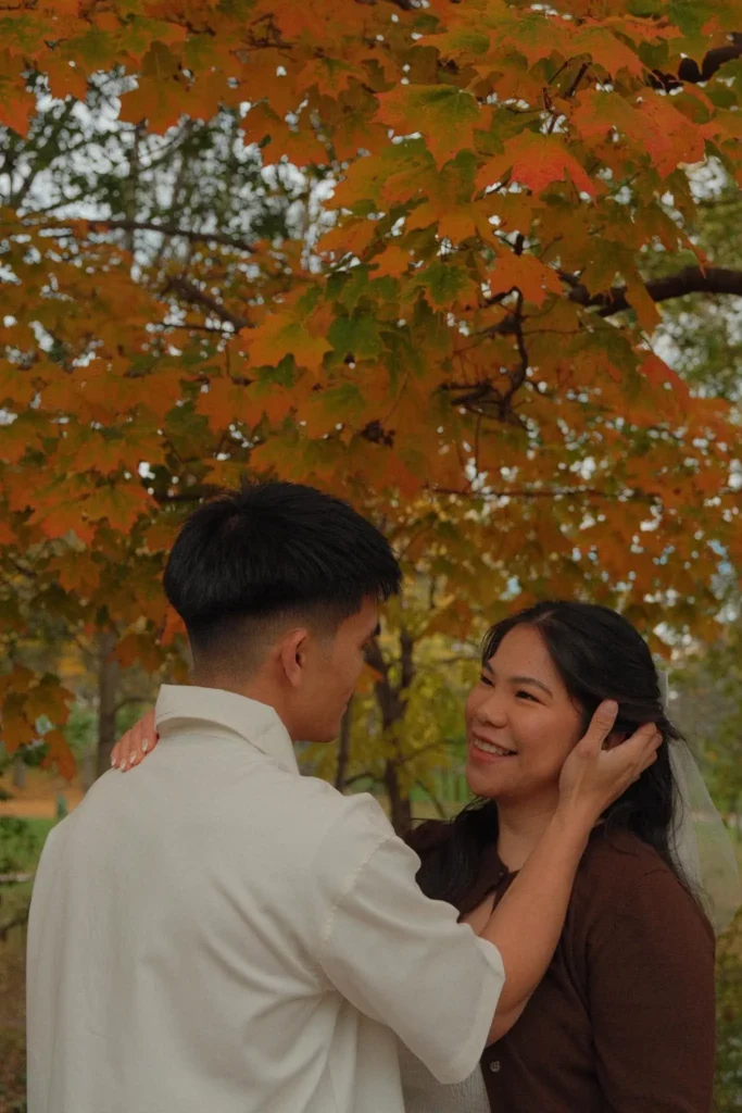 Under an orange maple, Earl tucks Den's hair behind her ear