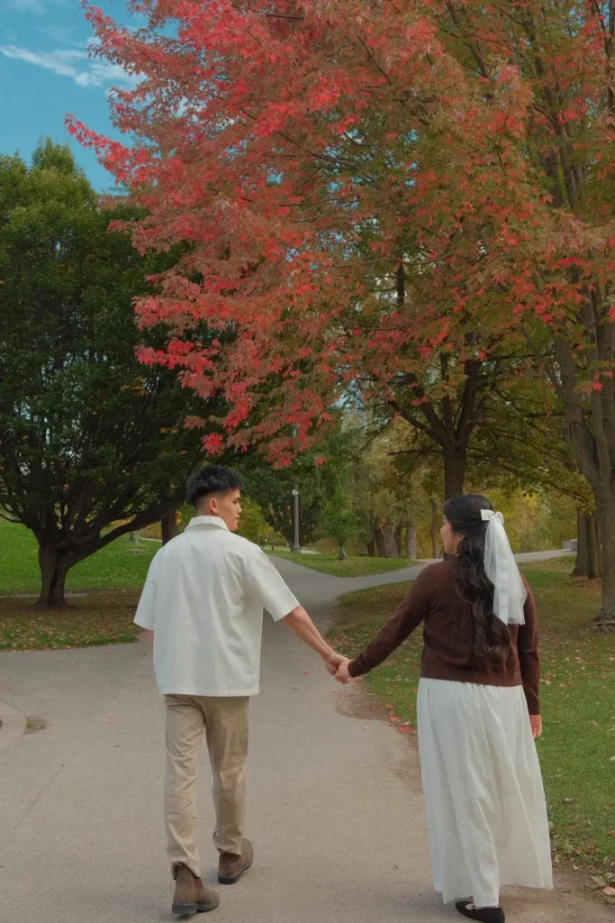 Walking hand in hand beneath a red maple