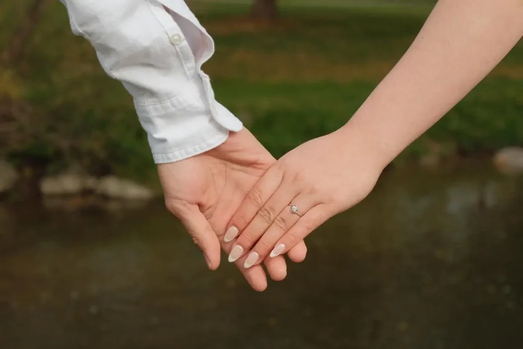Their hands linked, her engagement ring catching the light